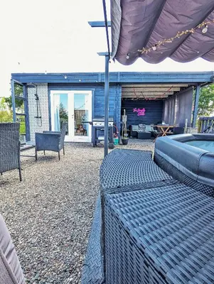 a patio with chairs and a table and a house at Rural Private Lodge - With Hot Tub - Outdoor Kitchen and Covered Lounge for Two in Crook of Devon