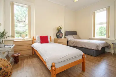 a bedroom with two beds and two windows at Lotus Studio near Lanark in Carstairs