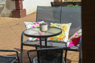 a table and chairs with pillows on a patio at Lotus Studio near Lanark in Carstairs