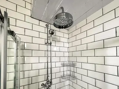a bathroom with a shower with white tiled walls at Osborne Place in Rothesay