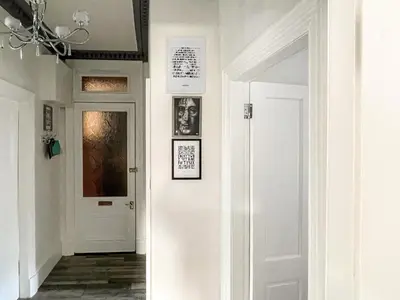 a hallway with a white door and pictures on the walls at Osborne Place in Rothesay
