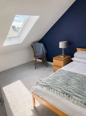 a bedroom with a bed and a chair and a window at Light & Spacious Loch Lomond Apartment in Alexandria