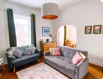 a living room with a couch and a mirror at Light & Spacious Loch Lomond Apartment in Alexandria