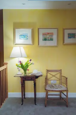 a table and a chair and a lamp and flowers at Claggan Farmhouse, Loch Tay in Aberfeldy