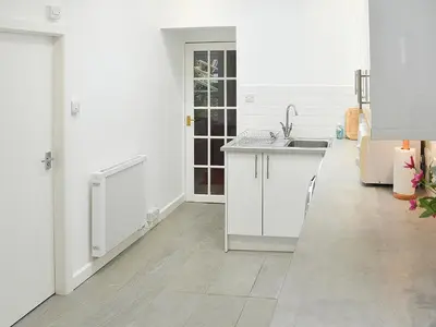 a white kitchen with a sink and a counter at Bay View in Brodick