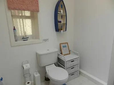 a white bathroom with a toilet and a mirror at Bay View in Brodick