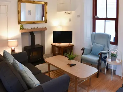 a living room with a couch and chairs and a fireplace at Bay View in Brodick