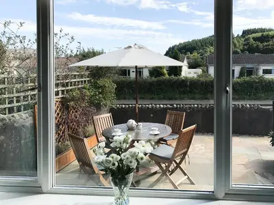 a table and chairs with a vase of flowers and an umbrella at Larkfield in Lamlash