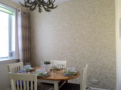 a dining room table with chairs and a chandelier at Larkfield in Lamlash