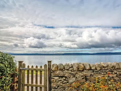 a wooden fence and a stone wall next to the water at The Apostles in Catacol