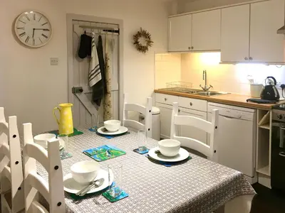 a kitchen with a table with chairs and a clock at The Apostles in Catacol