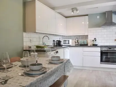 a kitchen with white cabinets and a table with dishes on it at 1 Hamilton Terrace in Lamlash