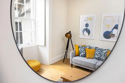 a living room with a chair and a mirror at JOIVY Chic Apartment near Stockbridge Market in Edinburgh