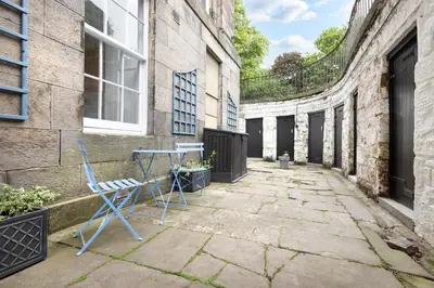 a patio with a blue chair and a table at JOIVY Chic Apartment near Stockbridge Market in Edinburgh