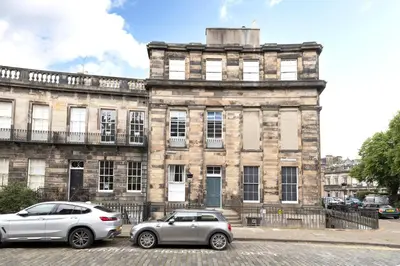 two cars parked in front of an old building at JOIVY Chic Apartment near Stockbridge Market in Edinburgh