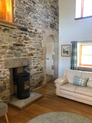 a living room with a stone fireplace and a couch at Old Tynribbie House - Comfortable Detached House in Appin