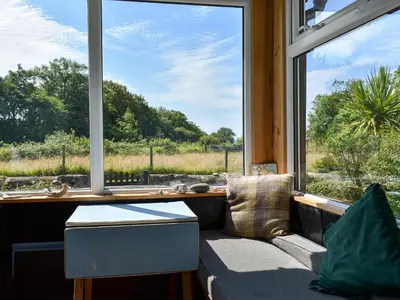 a living room with a couch and a large window at Burnside Cottage in Sliddery