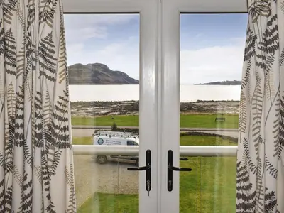 a window with a view of a boat in the water at Rivendell in Lamlash