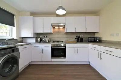 a white kitchen with white cabinets and a dishwasher at Signature - Harris House in Glasgow