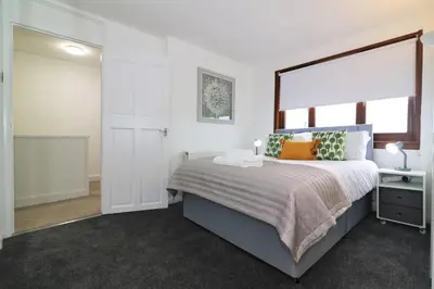 a bedroom with a bed and a large window at Signature - Barons Court in Paisley