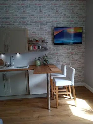 a kitchen with a wooden table and white chairs at On Yer Bike & Gone Fishin in Millport
