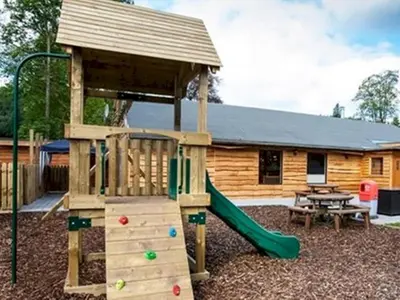 a wooden playground with a slide and a house at Beautiful 3BR Holiday Home in Stunning Location - Pass the Keys in Moffat