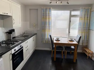 a kitchen with a table and a stove and a sink at Edgemont Annexe Oban in Oban