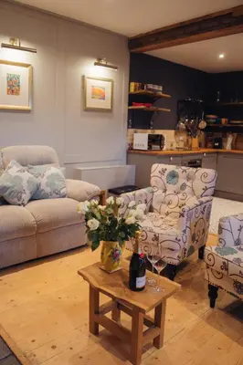 a living room with a couch and a table with a bottle of wine at Shepherds Forge, Loch Tay in Aberfeldy