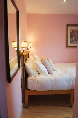 a bedroom with a bed with white sheets and a mirror at Shepherds Forge, Loch Tay in Aberfeldy