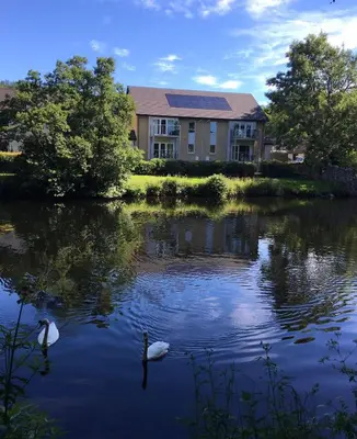 two swans in the water in front of a house at Beautiful Riverside Holiday Home in Callander