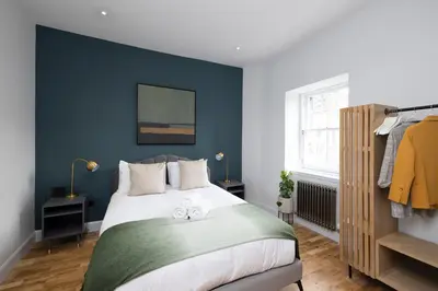 a bedroom with blue walls and a bed with two towels at Dragon Suites Luxury Serviced Apartments at Alva Street in Edinburgh