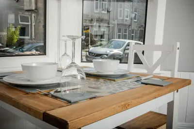 a wooden table with two cups and plates on it at Bonhill Getaway in Dumbarton