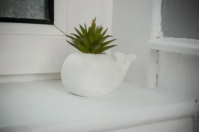a plant in a white vase sitting on a window sill at Bonhill Getaway in Dumbarton