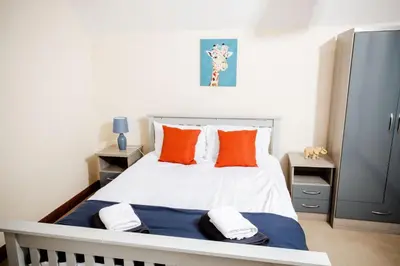 a bedroom with a white bed with orange pillows at Rigside House in Douglas