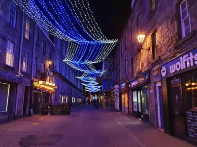 an empty city street with christmas lights on buildings at Lovely 2 bedroom flat in the heart of the city in Edinburgh