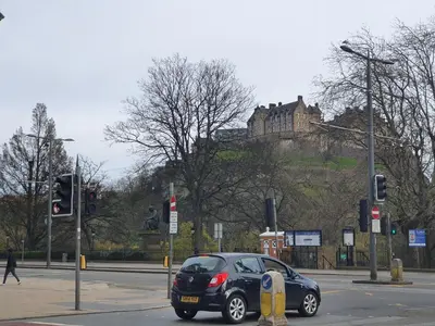 a small black car driving down a street with a castle at Lovely 2 bedroom flat in the heart of the city in Edinburgh