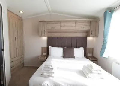 a bedroom with a large white bed with towels on it at Bennane Shore Holiday Park in Lendalfoot