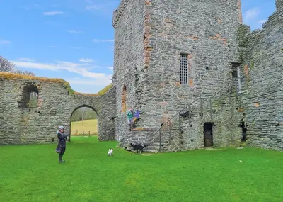 a person and a dog standing in front of a castle at Loch Shuna Lodges in Craobh Haven