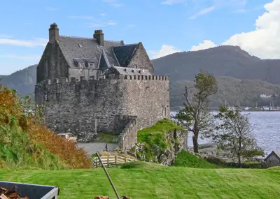 a castle on the shore of a body of water at Loch Shuna Lodges in Craobh Haven
