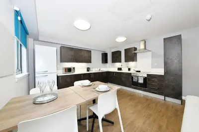 a kitchen with a wooden table and white chairs at HFS The Mill House Edinburgh in Edinburgh