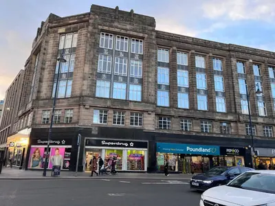 a large brick building on a street with people walking in front at Apartment with City Views - Sleeps 3 in Edinburgh