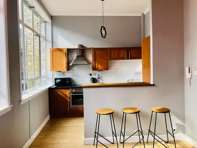 a kitchen with wooden cabinets and two stools at Apartment with City Views - Sleeps 3 in Edinburgh
