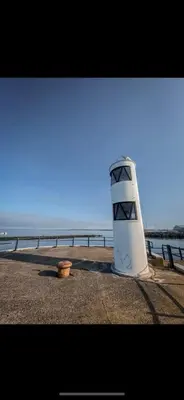 a white object sitting on the beach near the water at Dalblair Apartment in Ayr