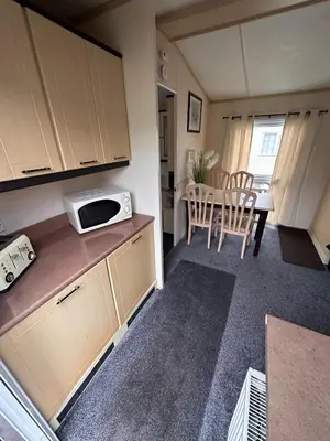 a small kitchen with a table and a microwave at 2 Bedroom Caravan Located in Uddingston, Glasgow at Maryville Caravan Site in Uddingston