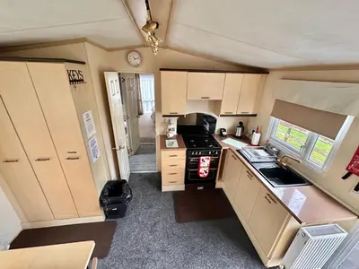 a kitchen with white cabinets and a black stove at 2 Bedroom Caravan Located in Uddingston, Glasgow at Maryville Caravan Site in Uddingston