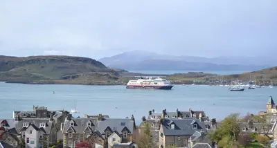 a boat in a large body of water with houses at Benvoulin Bothy - luxury pod with stunning views in Oban