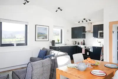 a kitchen and a living room with a table at Castlehill cabin with a hot tub in Peebles