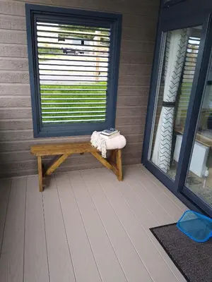 a bench on a porch with a window and a towel at The Cuddies in Balloch
