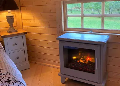 a fireplace in a room with a bed at Seal Point Cabin - Luxury Glamping in Cairndow