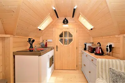 a kitchen in a log cabin with a sink and a stove at Seal Point Cabin - Luxury Glamping in Cairndow